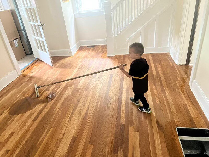 cute kid cleaning a wooden floor with a mop