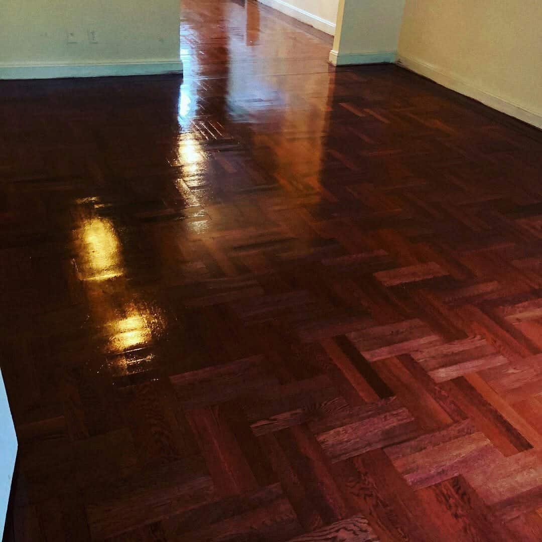 Freshly refinished dark wood flooring with a high gloss polyurethane shine in a bright NYC apartment.