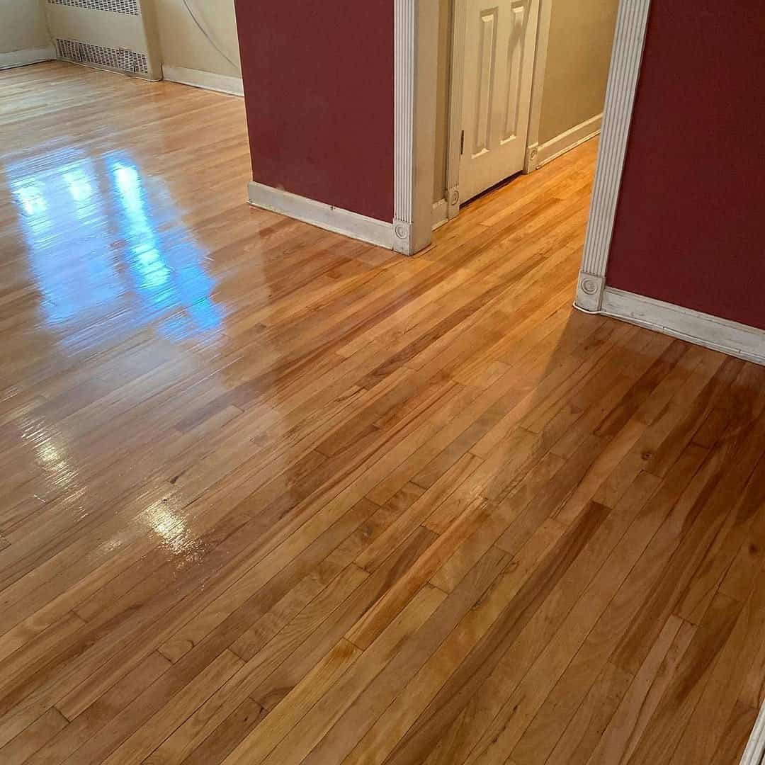 Worker carefully installing new walnut floorboards in a classic NYC brownstone living room.