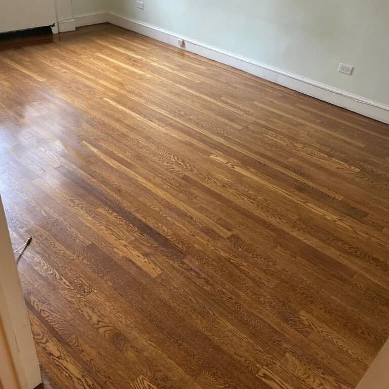 Professional floor sander smoothing out old hardwood planks in a classic NYC apartment.