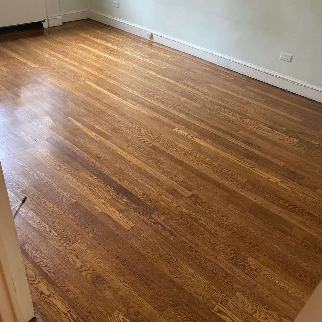 Professional floor sander smoothing out old hardwood planks in a classic NYC apartment.
