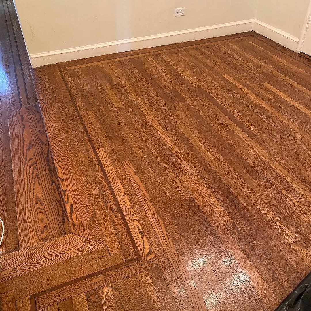 A fresh coat of dark wood stain being applied to newly sanded oak flooring.