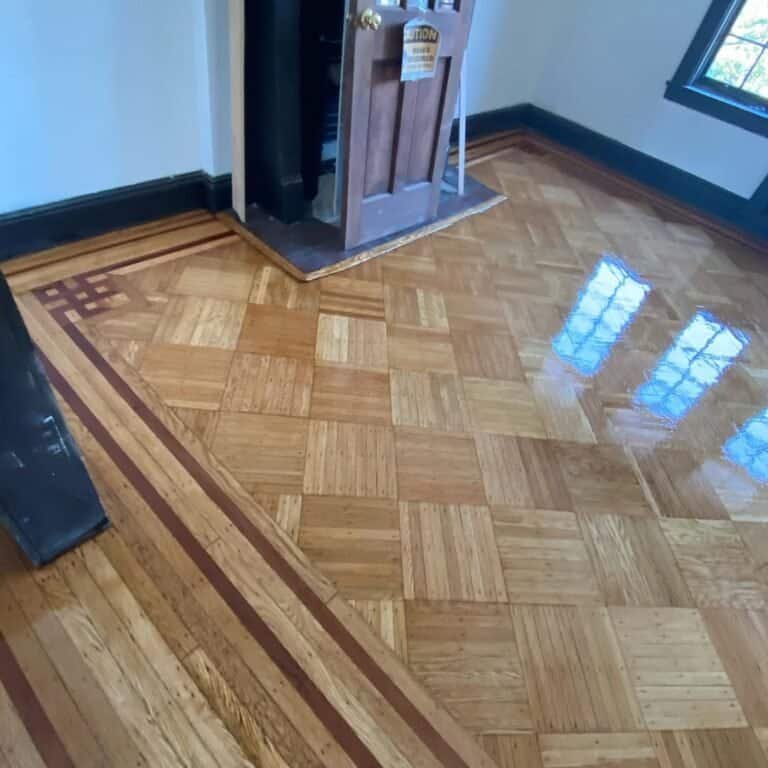 Worker repairing a custom wood floor border in a Downtown Brooklyn home during a professional refinishing project.