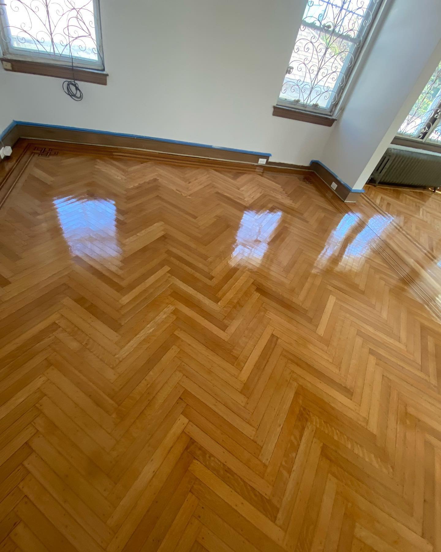 Wide view of a bright room in Park Slope with freshly finished high-gloss hardwood flooring.